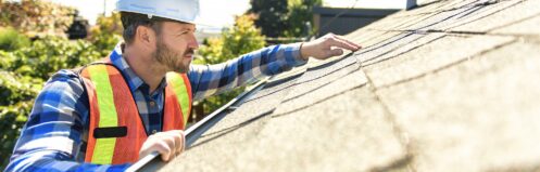 Roofer in a hard hat inspecting a roof
