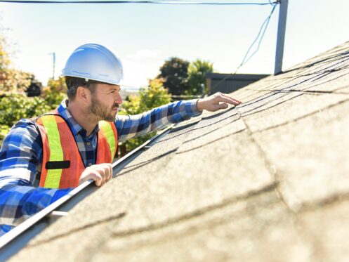 Roofer in a hard hat inspecting a roof