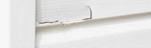 Closeup of cracked white siding on a home